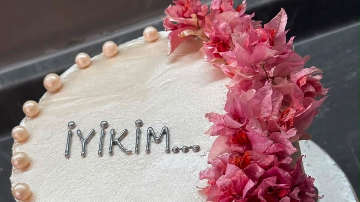 A blush cake with pearl detailing and a cascade of pink flowers