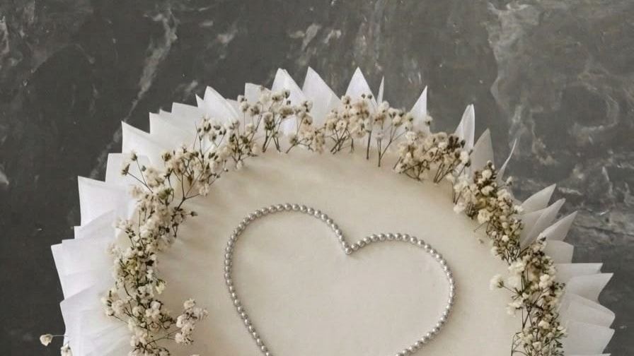 An engagement cake with a pearl heart and a dried-flower wreath