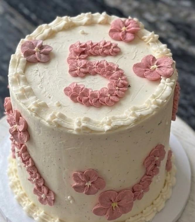 Cremefarbene Geburtstagstorte mit einer Fünf aus rosa Spritzblüten