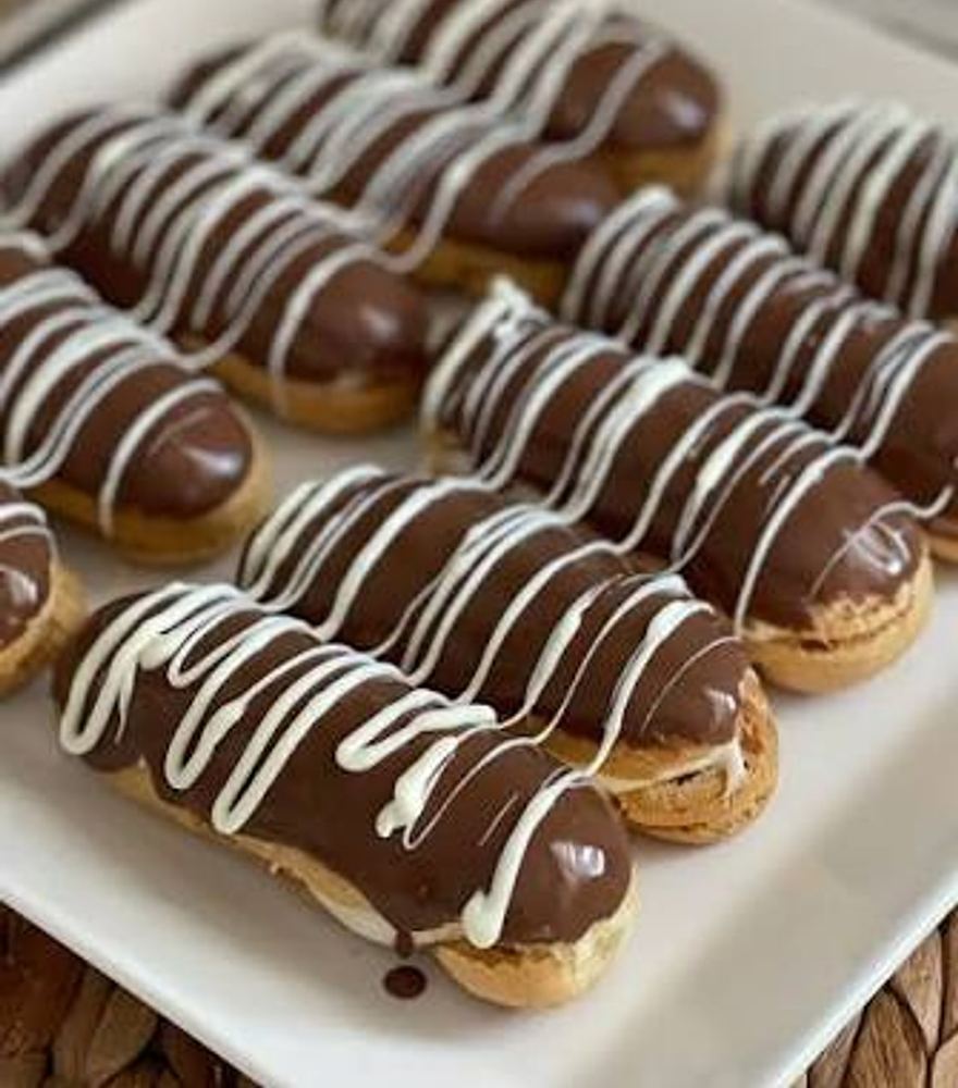 Ein Tablett mit schokolierten Éclairs und weißer Schokoladenzeichnung
